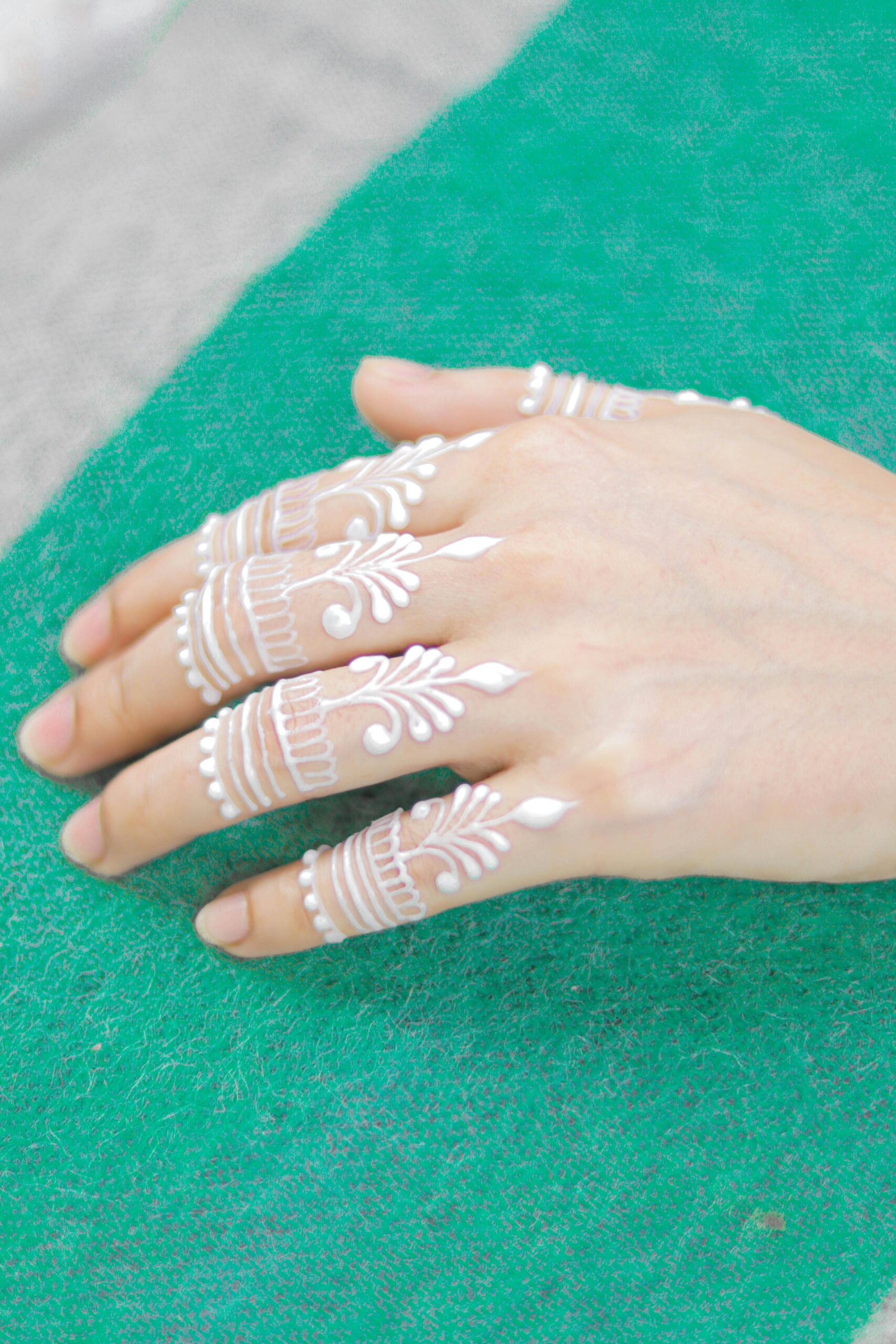 Elegant white henna patterns on hand, showcasing traditional body art with a modern twist.